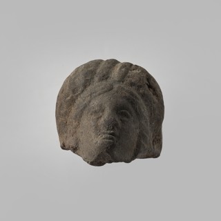 Head of a female figurine, preserved from the chin up. High hairstyle with a wreath above the