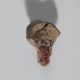 Head of a terracotta female figurine, with part of the neck and a fragment of a robe preserved.