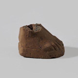 Fragment of a terracotta figurine showing two feet placed side by side on a flat, rounded base.