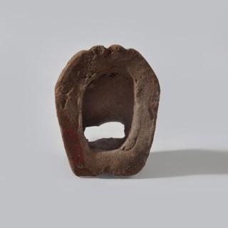 Fragment of a terracotta figurine showing two feet placed side by side on a flat, rounded base.