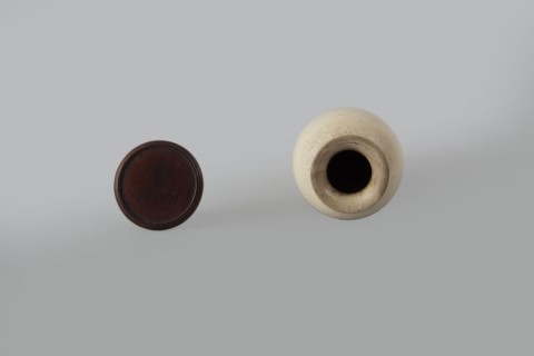 Cylindrical porcelain vase tapering toward the bottom with a flat rim; light cream glaze with fine