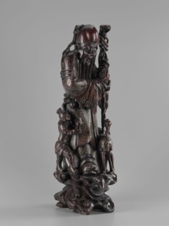 Deity of Longevity Shouxing/Shoulao holds a long traveling staff and a peach of immortality. His