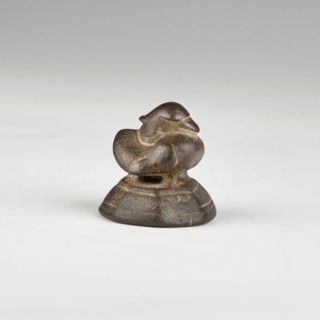 Weight in the shape of a duck standing on two short legs and a similar support, on a wide,