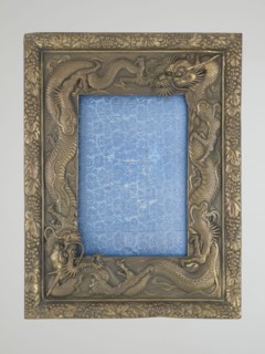 Frame with glass and raised back support covered with blue silk with floral patterns; originally