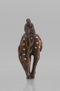 Netsuke in the shape of Fukurokuju riding a deer. The deer has all its legs put together so that