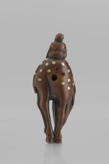 Netsuke in the shape of Fukurokuju riding a deer. The deer has all its legs put together so that