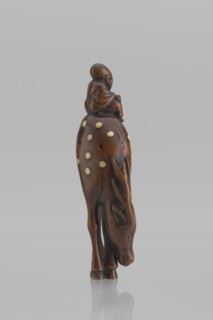 Netsuke in the shape of Fukurokuju riding a deer. The deer has all its legs put together so that