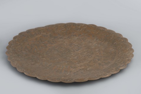 Plate, flat without a distinct rim. Decorated with a dense arabesque in the hataji style and an