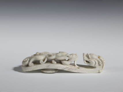 Belt clasp. Handle: stylized lizard-dragon qilong. Milky-white jadeite. Full-plastic carved head,