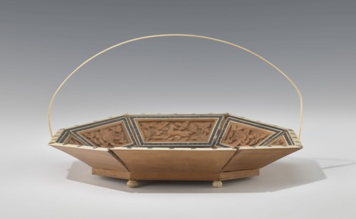 Basket. Octagonal shallow wooden basket with an ivory rim and handle. Inside the basket is a relief