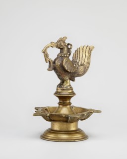 Oil lamp; round base supporting a pentagonal oil vessel with a bird figurine above. 19th century,