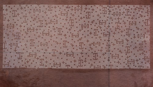 A katagami dyeing stencil cut into a pattern composed of small crosses, squares, and lines against