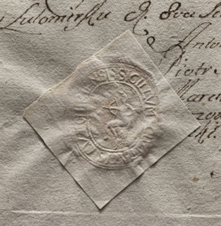 Oval seal impression of the town of Lutomiersk. In the central part—a seated figure holding a