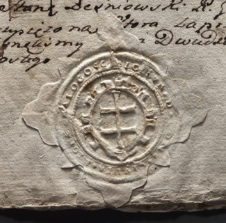 Round seal impression of the town of Malogoszcz. In a decorative cartouche, a double cross — the