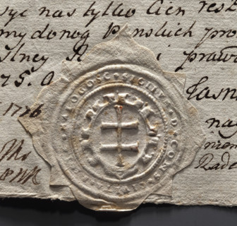 Round seal impression of the town of Malogoszcz. In a decorative cartouche, a double cross — the