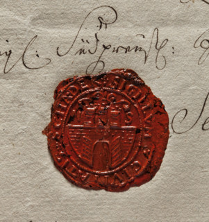 Oval wax impression of the seal of Szadek. Town wall with an open gate, on it three towers with