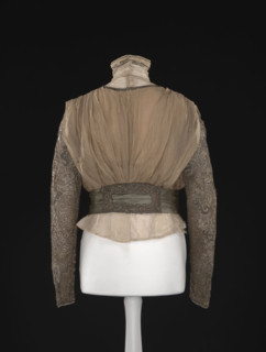 Blouse. Made of beige-gold muslin, short, bloused, fitted at the waist with a belt draped in three