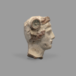 Head of a figurine of Dionysus. Head of a young man with a face devoid of expression, with a wide,