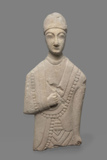 Fragment of a votive figure of a man. The fragment depicts a standing man dressed in a tutulus and