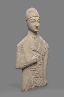 Fragment of a votive figure of a man. The fragment depicts a standing man dressed in a tutulus and