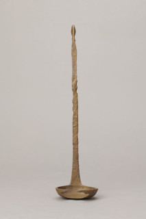 Shallow dipper with a quadrilateral handle narrowed at the top. The end of the handle is in the