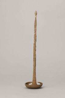 Shallow dipper with a quadrilateral handle, narrowed at the top. The end of the handle is in the