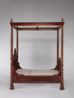 Four-poster double bed with flat pediments topped with a wavy pattern, framed by tall spiral
