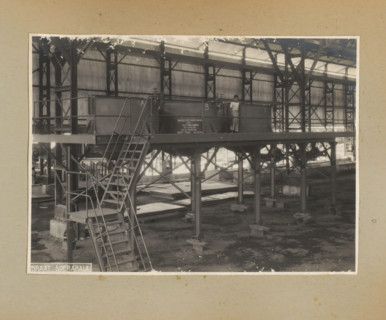Platform with cooking pots, photograph, Album page with a photo of the interior of a factory hall