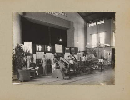 Men posing in the factory by a display of machines, album page, photograph, Album page with a photo