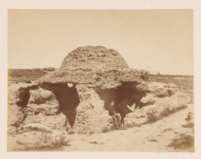 Canopy, house of wood stones?, with a man in front of it, photograph, with a man in front of it.,