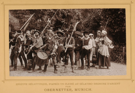 View of a group of unknown persons, one with a drum, probably re-enacting a fight or battle, page,