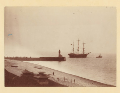 Tugboat takes sailing ship in tow at a harbor pier, photograph, Part of a French artist's album., c