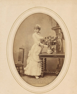 Portrait of a woman standing by a table with flowers, album page, photograph, cabinet photograph,