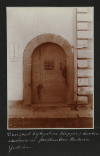 Closed door between the city hall and the post office in Batavia, on the left a sign of the ANIW,
