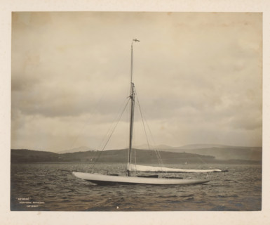 Sailing ship Deirdré in the water with a hilly landscape in the background, album page, photograph,