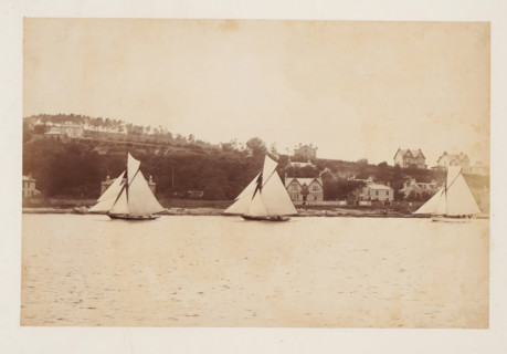 Three sailing ships, including the Coila, at sea with a landscape with buildings in the background,