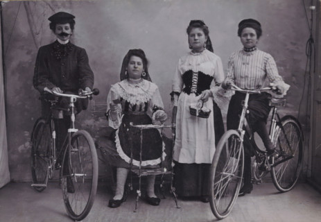 Group portrait of four unknown girls in traditional costume with bicycles, photograph, inscription:
