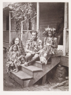 Portrait of a family from Tahiti, sitting on a step in front of the house where they work as