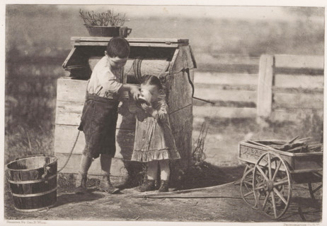 Boy lets a little girl drink water at a well, page, photomechanical print, photographer: Geo B.