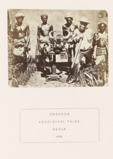 Group of four men from the Korku tribe and a British hunter around a table with a head of bison on