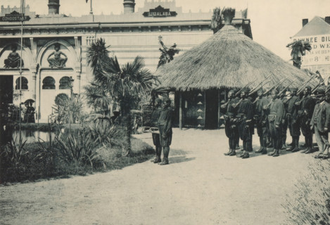 Congo, Troupe indigène, Group of men with instruments and weapons in a recreated Congolese village