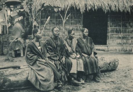 Groupe de Congolais, Four men sit on a tree trunk in a recreated Congolese village at the Antwerp