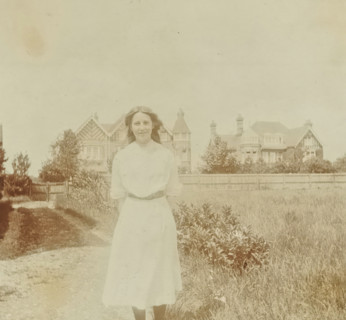Marjorie in a rural setting with a building in the background in Bexhill-on-Sea in England, 1913,