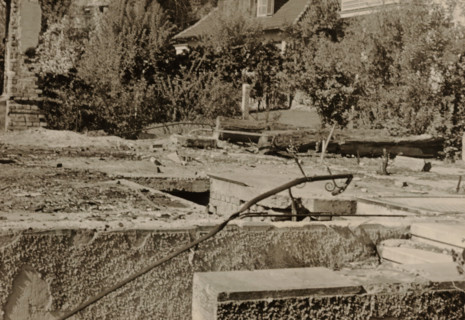 Top of part of a ruin, with a tree-lined house in the background, photograph, with a tree-lined