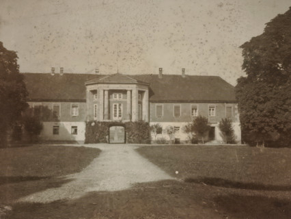 Front view of a country house with a gazebo-shaped central section, with trees on either side and a