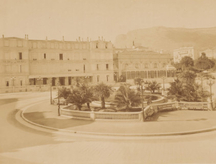 Square with roundabout with palm trees and pond in the middle and houses around it, photograph,