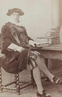 Portrait of a man in a suit sitting at a table, identified as N. Dirkzwager, album page,