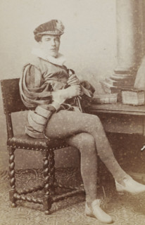 Portrait of a man in a suit sitting at a table with books, identified as J. Wiarda, album page,