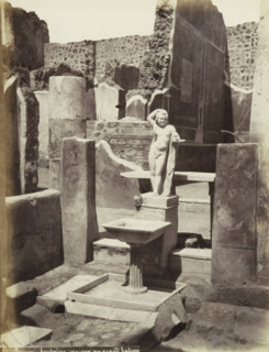 Pompeii fountain house with a large balcony, Remains of a house in Pompeii with a statue and a