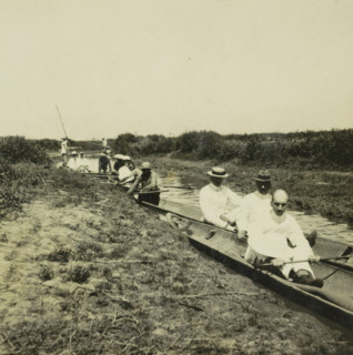 Some boats on a narrow canal, probably the Sungai Martapura river, with both Europeans and original